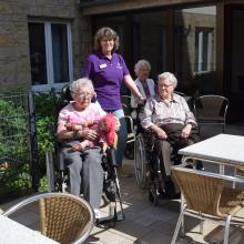 Unsere Bewohnerinnen und Bewohner wohnten dem Konzert auf Gartenstühlen und Balkonen bei schönstem Sommerwetter bei, hier mit Alltagsbegleiterin Bettina Manz.